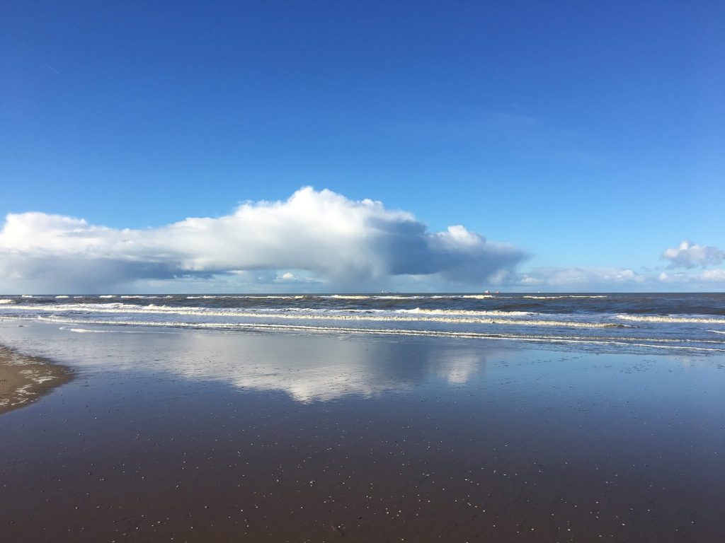 Clouds reflected in the water on a beach in Katwijk